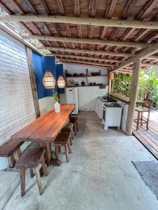 an outdoor kitchen with a wooden table and benches at Casa do Rio in Caraíva