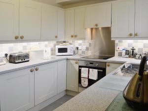a kitchen with white cabinets and white appliances at Isfryn in Llanystumdwy