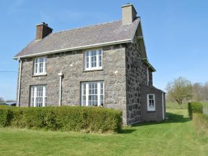 an old stone house with a hedge in front of it at Isfryn in Llanystumdwy