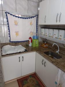 una cocina con armarios blancos y fregadero en Apto Texas em Balneário Camboriú-SC, en Balneário Camboriú