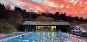 a pool in front of a building with a sunset at Mófellsstaðakot in Borgarnes