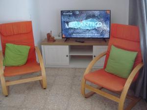 コティージョにあるApartamento Cotilloの- オレンジ色の椅子2脚、テレビ1台