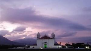 a white building with a tower with a green light at El Mirador in Juayúa