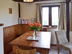 een eettafel met een vaas met bloemen erop bij Weach Barton Granary in Bideford