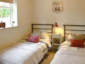 a bedroom with two beds and a clock on the wall at Ferncliffe Cottage in Snitter