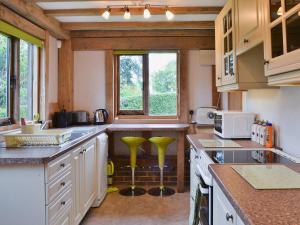 WoodmancoteにあるLittle Timbersの白いキャビネットと緑のスツール付きのキッチン