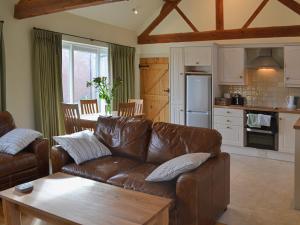 a living room with a brown leather couch and a kitchen at Jumbos Stable in Alderminster