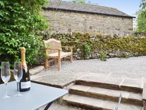 a table with a bottle of wine and two wine glasses at Prospect Cottage in Kettlewell