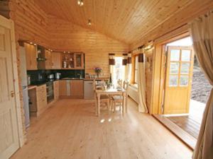 a kitchen with a table and chairs in a house at Bracken Log Cabin - S4468 in Glenfarg