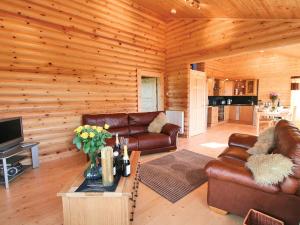 a living room with leather furniture in a log cabin at Bracken Log Cabin - S4468 in Glenfarg