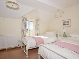 two beds in a white room with a window at Cefn Bach in Capel Garmon