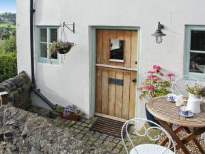 a wooden door of a white house with a table and chairs at The Wee House On The Hill in Wirksworth