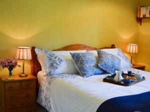 a bed with blue and white pillows and a tray on it at Cowbeech Farm Cottage in Herstmonceux