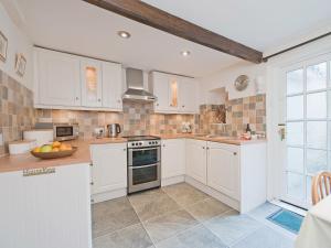 a kitchen with white cabinets and a counter top at Holly Cottage in Crowthorne