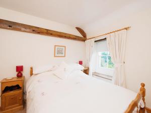 a bedroom with a white bed and a window at Holly Cottage in Crowthorne