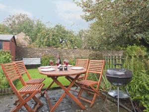 een tafel en stoelen met een barbecue en een grill bij Holly Cottage in Crowthorne