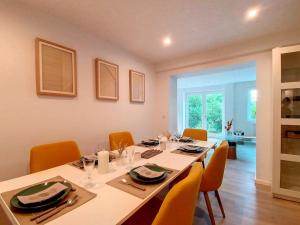 a dining room with a long table with orange chairs at GENVAL - THE LAKE SIDE HOUSE in Rixensart