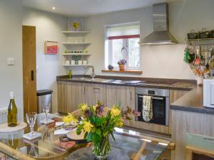 a kitchen with a glass table with flowers on it at Fishermans Nook in Holne