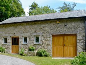 a stone house with wooden garage doors on it at Fishermans Nook in Holne