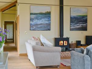 a living room with a fireplace and two chairs at Partridge Barn in Sculthorpe