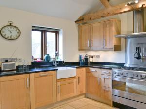 a kitchen with wooden cabinets and a clock on the wall at Partridge Barn in Sculthorpe