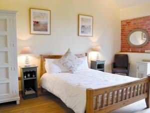 a bedroom with a bed and a chair and a mirror at Partridge Barn in Sculthorpe