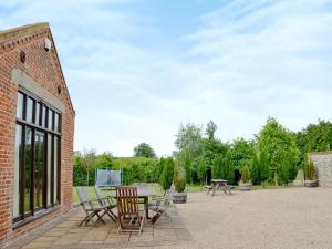 a patio with a table and chairs on a brick building at Partridge Barn in Sculthorpe
