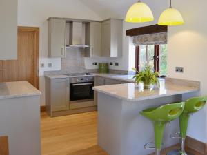 a kitchen with white cabinets and green bar stools at Swallows Retreat in Hartland