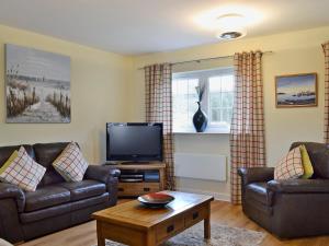 a living room with two leather couches and a tv at Seaview in Garlieston