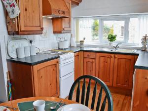 uma cozinha com armários de madeira, uma mesa e um fogão em The Stables At Old Vicarage Cottage em Abergele