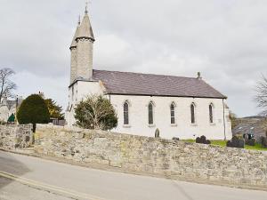 uma igreja com uma parede de pedra e um campanário da igreja em The Stables At Old Vicarage Cottage em Abergele