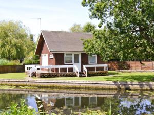 a red house next to a body of water at Silver Birches-af46 in Horning