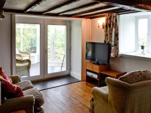 a living room with a tv and a sliding glass door at Cae Cynddelw in Pale