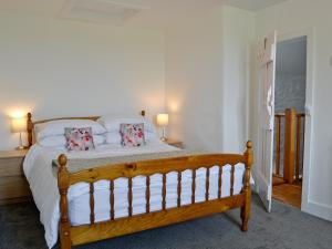 a bedroom with a wooden bed with white sheets and pillows at Cae Cynddelw in Pale
