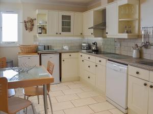 a kitchen with white cabinets and a table in it at 2 The Courtyard in Portreath
