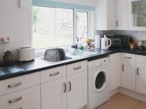 uma cozinha com um lavatório e uma máquina de lavar roupa em Bydand Cottage em Melness