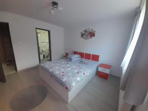 a white bedroom with a bed with red accents at Cabana Acasă la Delia in Gîrda de Sus