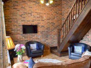 a living room with two chairs and a brick wall at Quince Cottage - 27443 in Sedlescombe