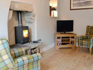 a living room with a fireplace and a tv at Holly Bank Cottage in Settle