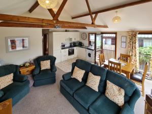 a living room with blue couches and a kitchen at Herons View - 28279 in Brundall