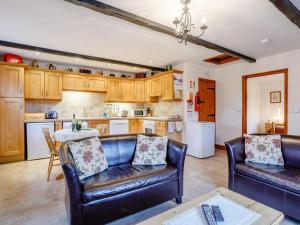 a living room with two leather couches and a kitchen at Lintel Barn - E5253 in Runcton Holme