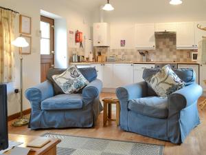 2 sillas azules en una sala de estar con cocina en Stables-23893, en Aylmerton