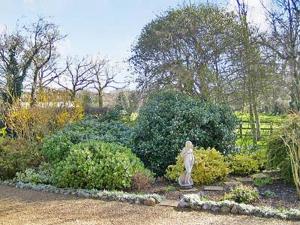 un jardín con una estatua en medio de unos arbustos en Stables-23893, en Aylmerton
