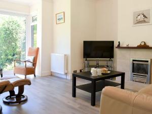 a living room with a tv and a couch and a table at Seascape in Sidmouth