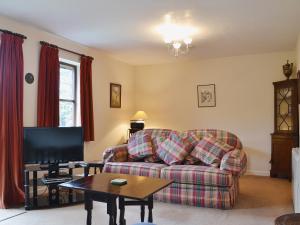 a living room with a couch and a tv at Strawberry Cottage in Kinlet