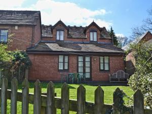 a brick house with a fence in front of it at Strawberry Cottage in Kinlet