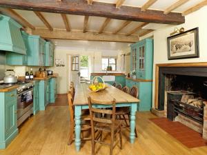 a kitchen with blue cabinets and a table with bananas on it at The Shooting Lodge in Acton Scott