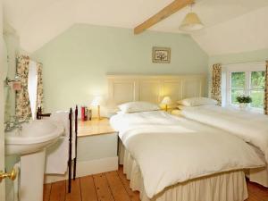 two beds in a room with a sink and a bathroom at The Shooting Lodge in Acton Scott