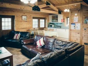 a living room with a leather couch and a kitchen at No, 6 Lake View Lodges - 28283 in Leake Common Side