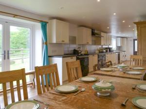 a kitchen with a wooden table with chairs and a dining room at Tutchenor Farmhouse in Beaworthy